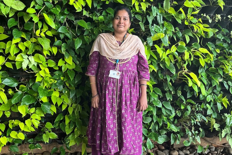 ZF alumnus standing in front of a green plant wall, sharing a return-to-ZF experience through the Where We Belong alumni program.