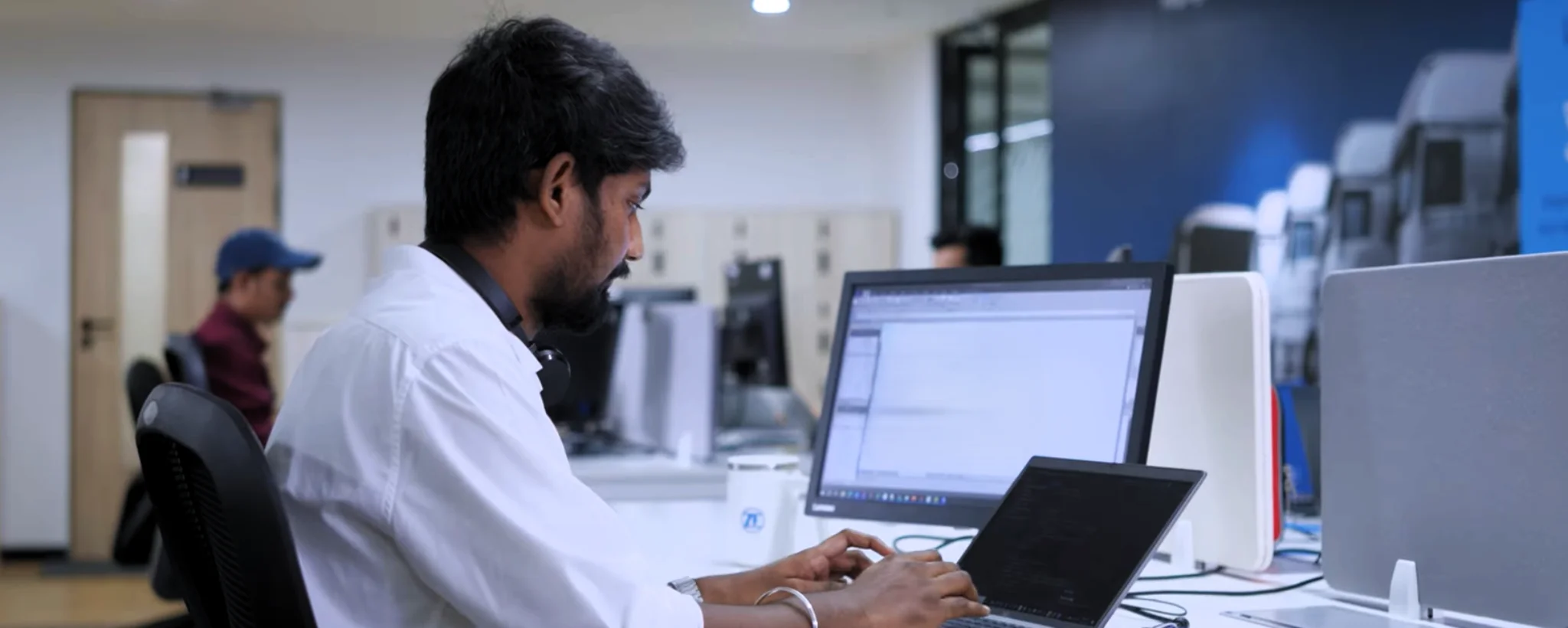 Early career professional working on a laptop in a corporate office environment in India