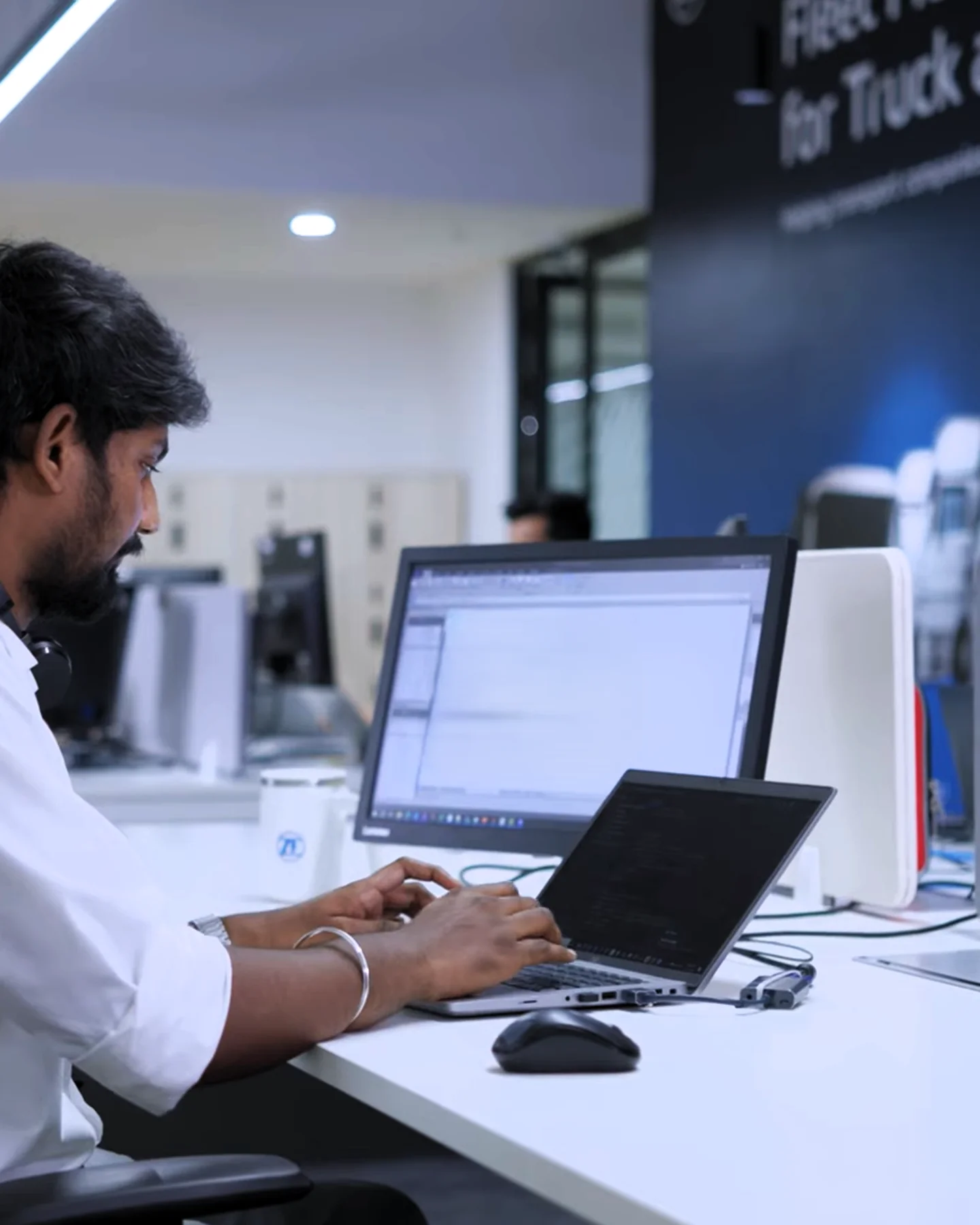 Early career professional working on a laptop in a corporate office environment in India
