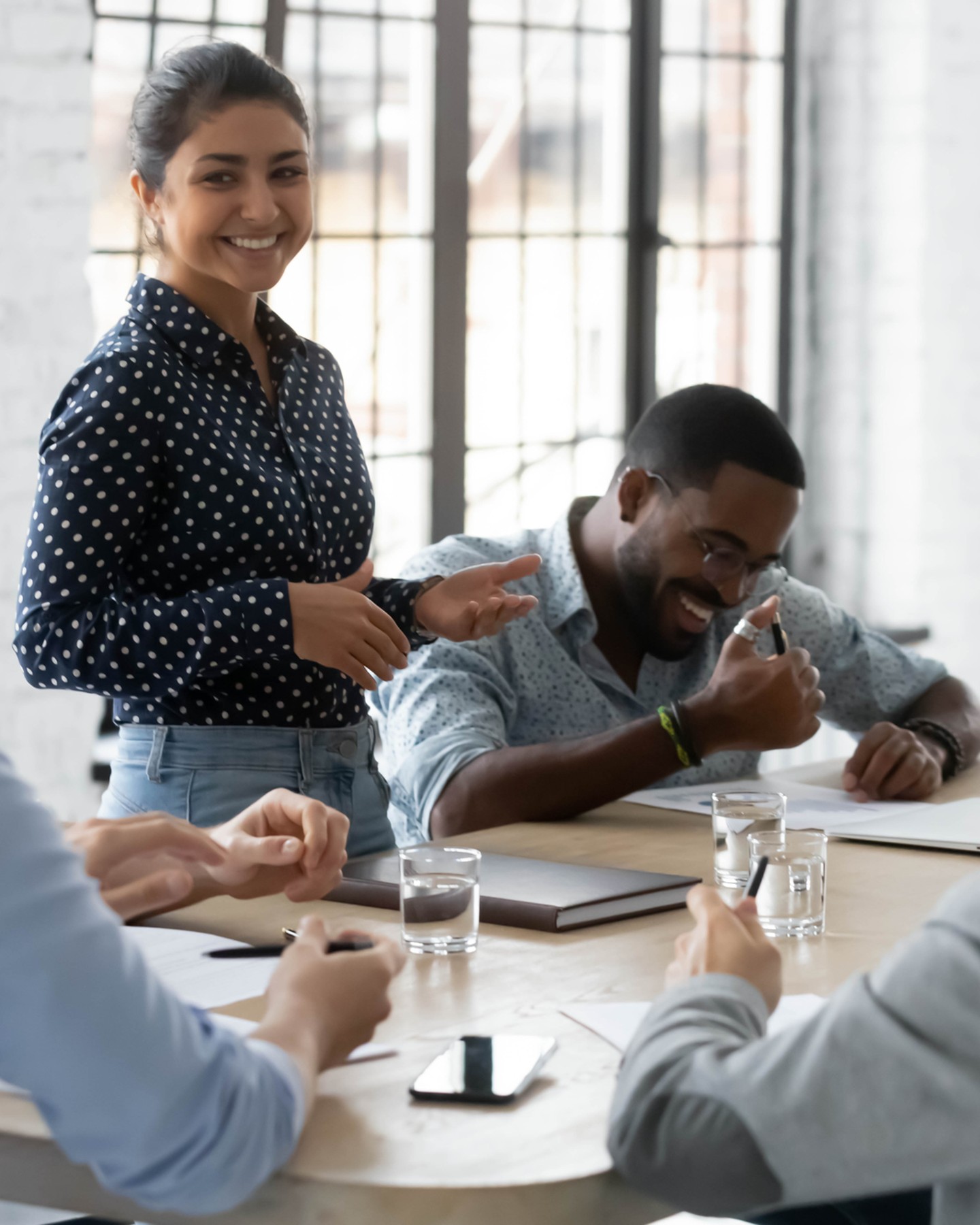Five people around a desk, smiling and laughing