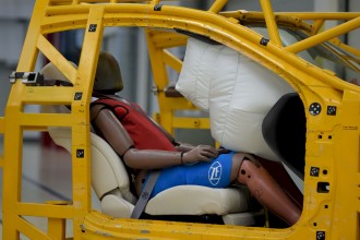 A dummy sitting in a test vehicle with a deployed airbag