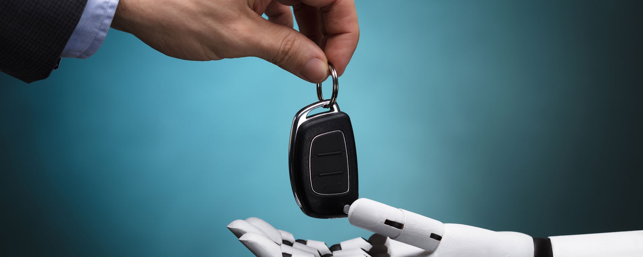 Human hand handing over car keys to robot hand.