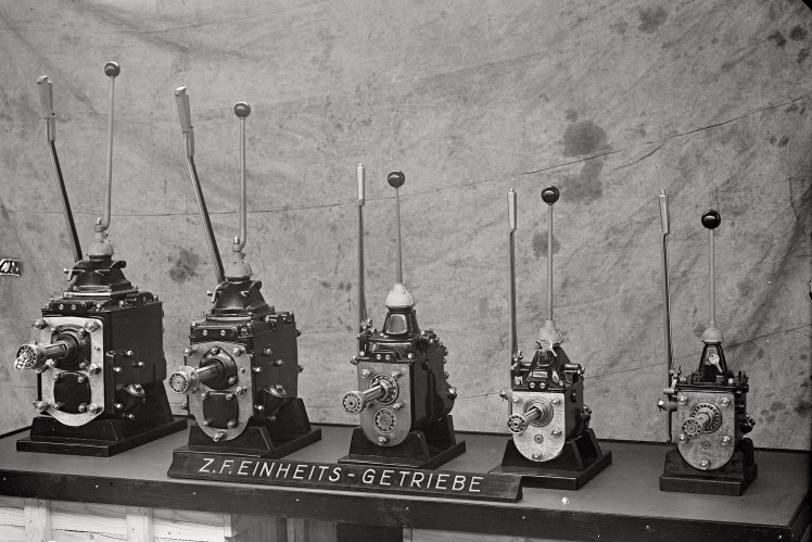 Auf einem Bild in schwarz-weiss sind fünf alte Einheitsgetriebe nebeneinander ausgestellt.