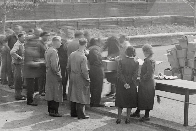 Auf einem Bild in schwarz-weiss stehen einige ZF-Mitarbeiter im Freien an einem Tisch und schauen Pläne oder ähnliches an.