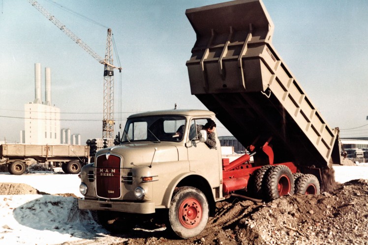 Das Farbbild zeigt einen Hauben-Lkw mit aufgestellter Kipplade beim Abladen.