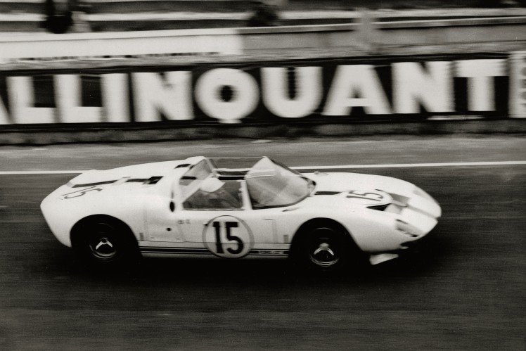 Das Bild in schwarz-weiss zeigt einen Ford GT 40 mit der Startnummer 15 von der Seite im Renneinsatz.