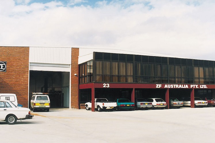 Das Farbbild zeigt ein Werksgebäude von ZF Australia mit diversen geparkten Fahrzeuge darunter und davor.