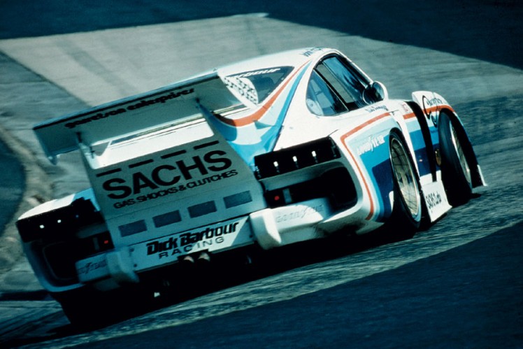 White car on race track viewed from behind.