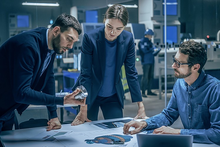 People bent over desk looking at product sample