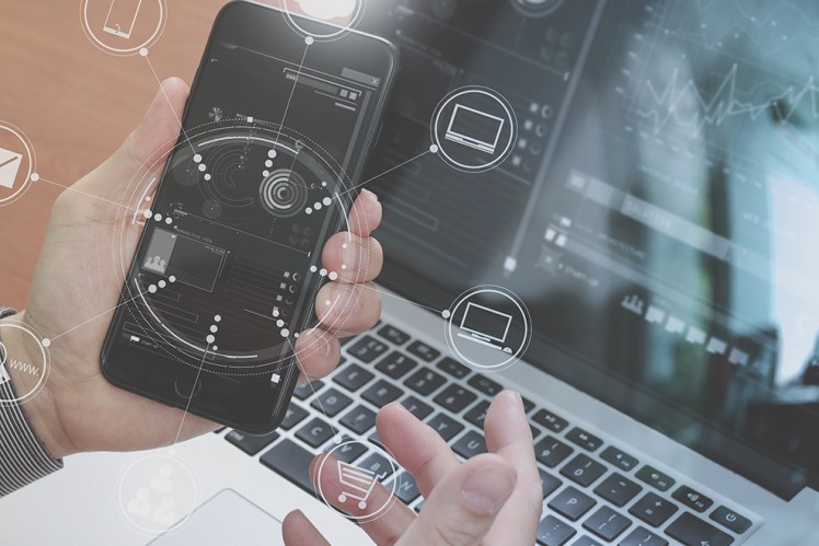 Person holding phone in front of laptop