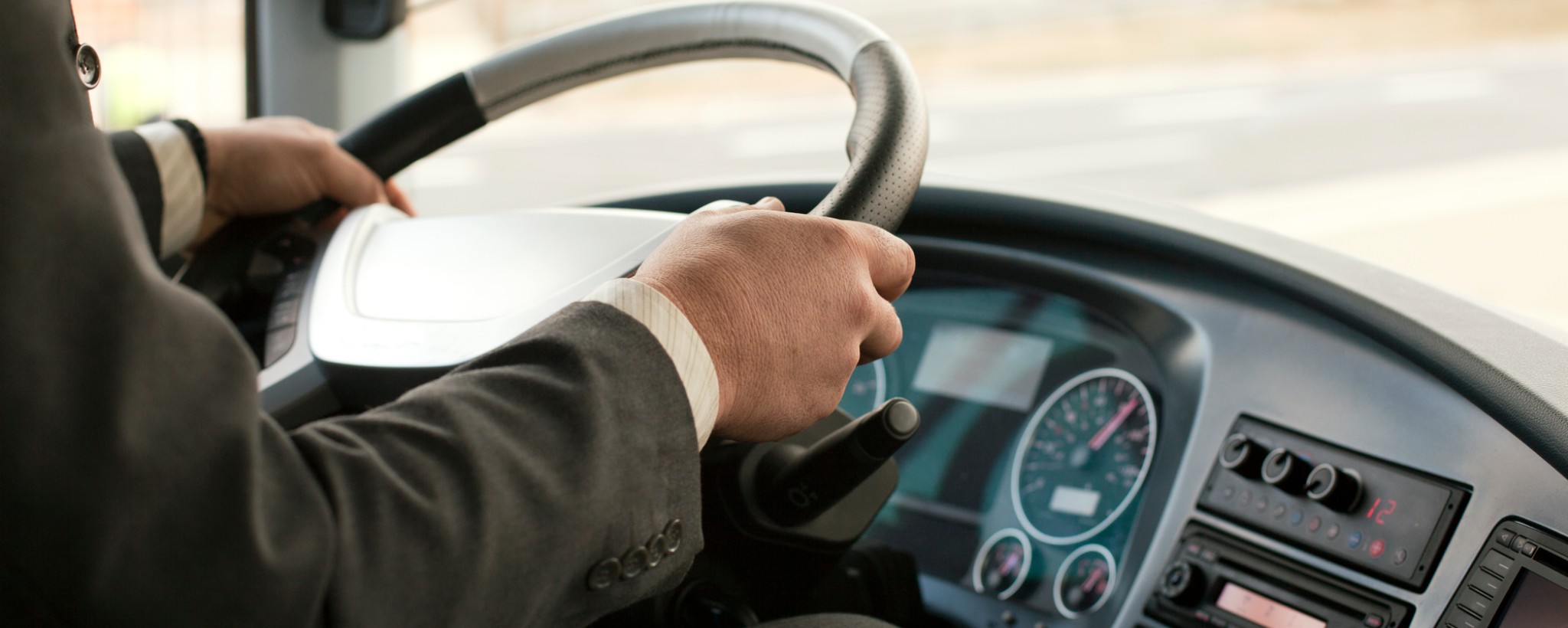 Mano del conductor sobre el volante y el tablero