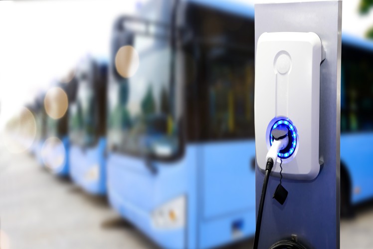 Close-up of an EV charger plugged into a city bus