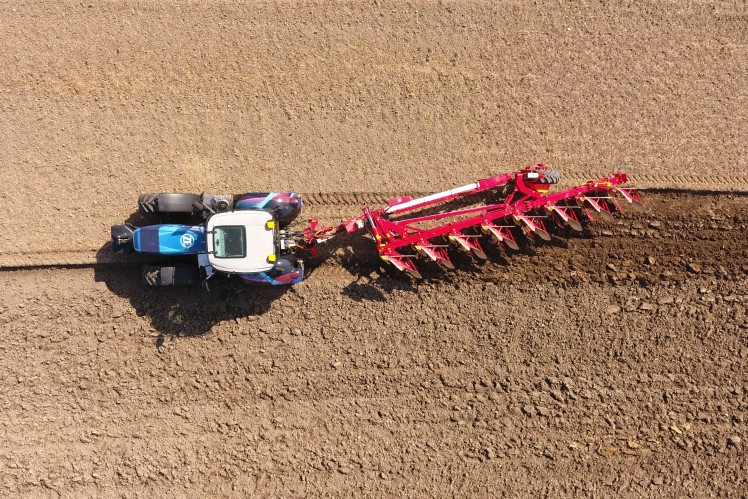 Traktor mit Pflug auf einem Feld aus der Vogelperspektive