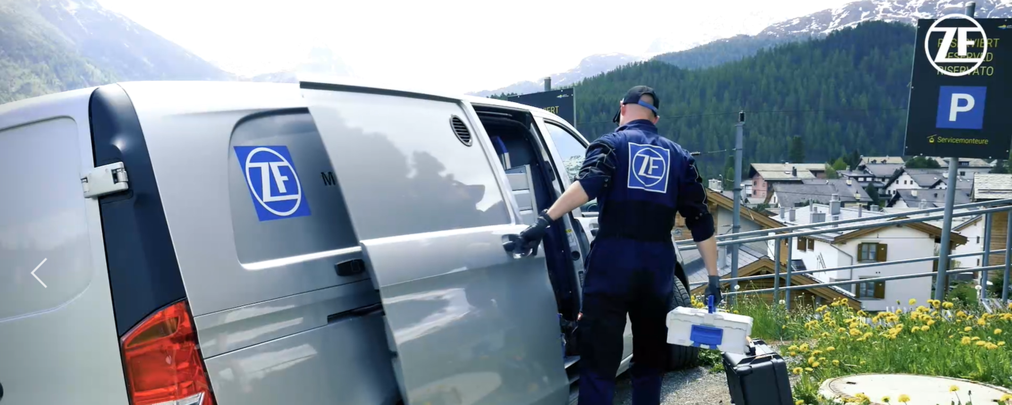 A ZF service employee is just removing his tools from a bus. A mountain landscape can be seen in the background.
