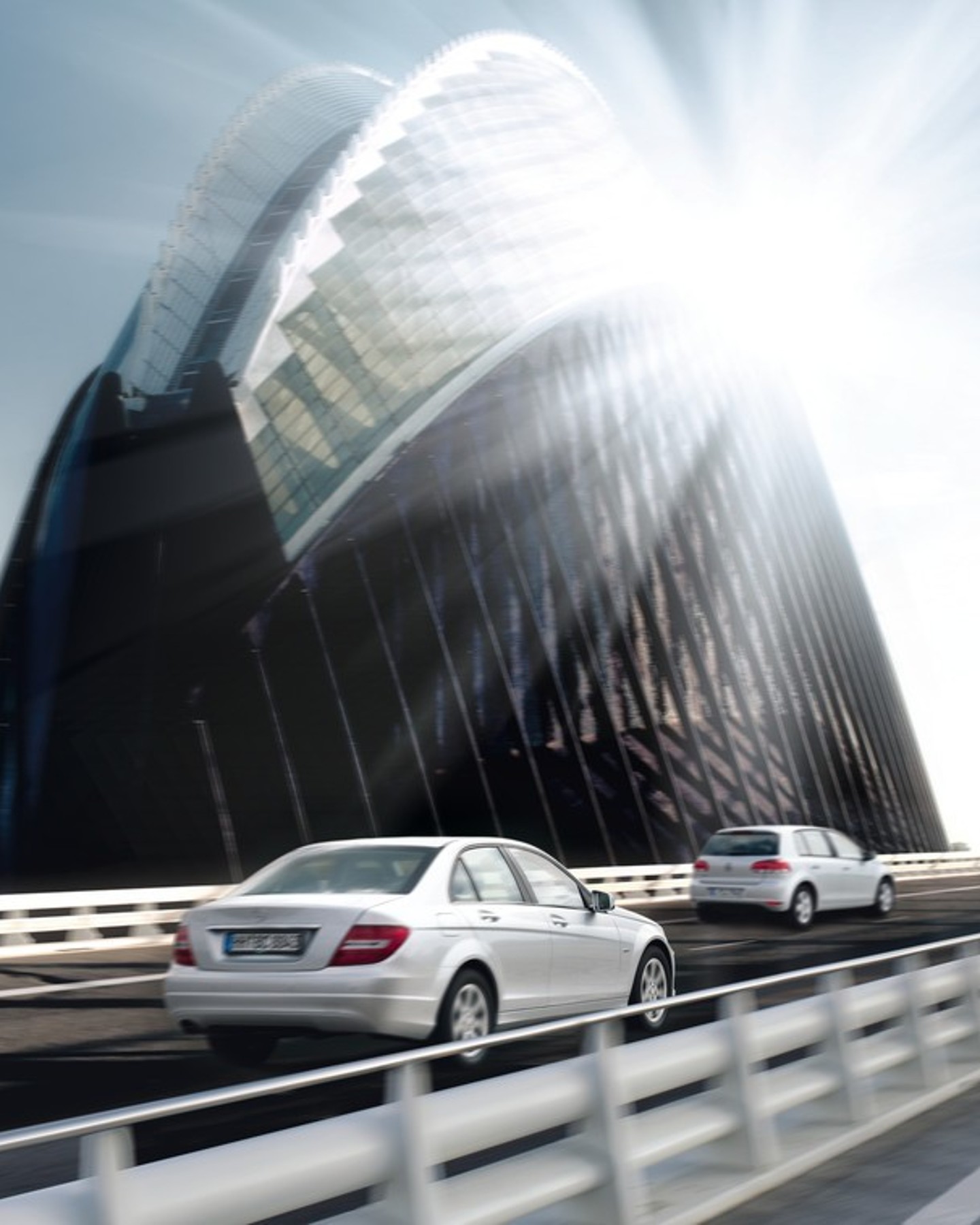 Silver car driving over bridge in bright sunlight