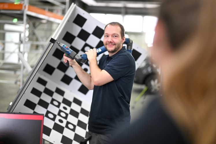 A man holds a calibration tool against a checkered calibration target.